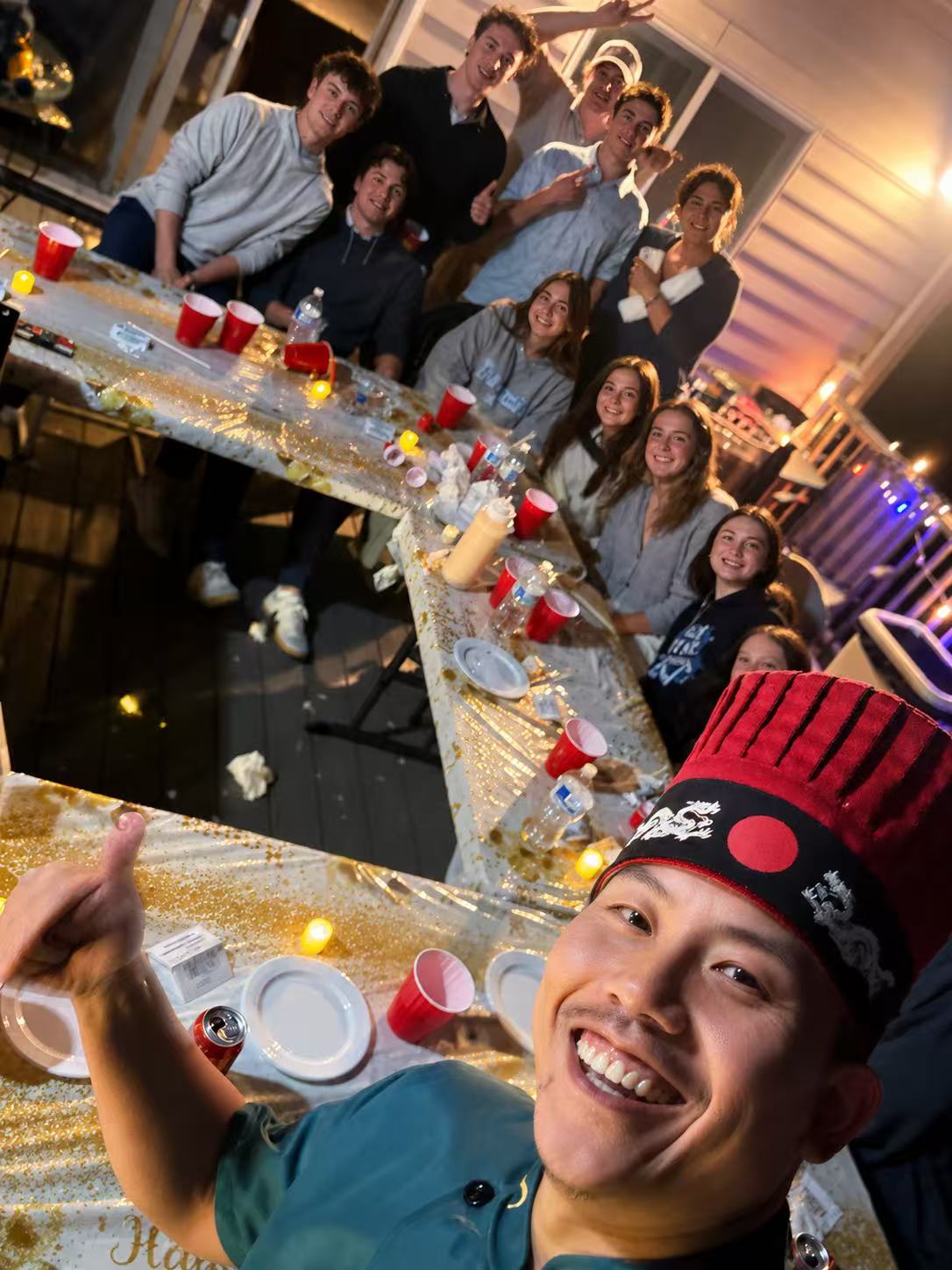Guests taking a group photo with the chef at night